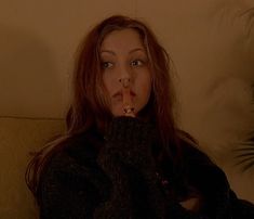 a woman sitting on a couch with her finger in her mouth