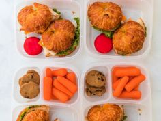 four plastic containers filled with sandwiches, carrots and other food items on a table