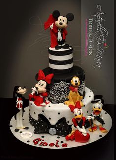 a mickey mouse cake with many different characters on the top and bottom tier, all decorated in black and white