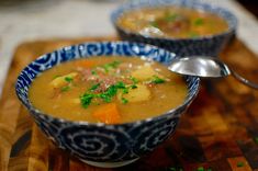 two bowls filled with soup on top of a wooden cutting board