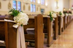 white flowers are tied to pews in a church