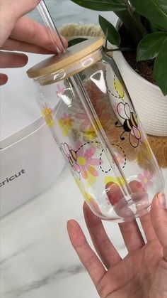 a person holding a glass cup with flowers on it