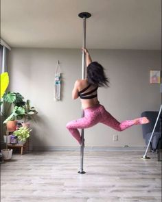 a woman is doing pole dancing in the living room