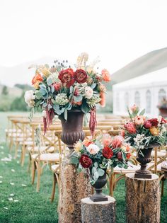 an arrangement of flowers in vases on top of wooden stumps at a wedding ceremony