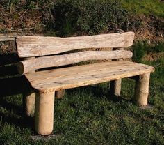 a wooden bench sitting on top of a lush green field next to a tree trunk