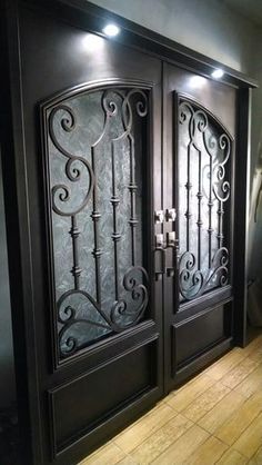 two black doors with intricate iron designs on the front and side panels, in a hallway