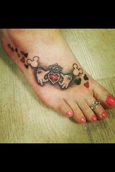 a woman's foot with mickey and minnie mouse tattoos on the top of it