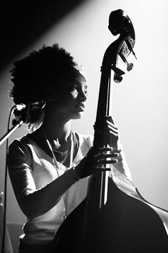 a woman holding a bass in front of a microphone