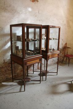 three glass cases sitting on top of a white floor next to a chair and table