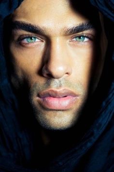 a man with blue eyes is wearing a hoodie and looking at the camera while he stares into the distance