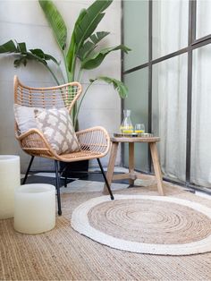 a living room with a rug, chair and side table in front of a window