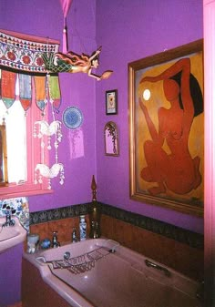 a bath tub sitting under a window next to a sink in a room with purple walls