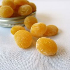 some yellow candies are in a metal bowl on a white tablecloth next to a can