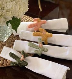 four napkins with embroidered cactus designs on them are sitting on a table next to a flower vase