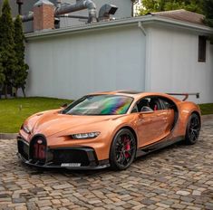 an orange bugatti is parked in front of a white building with black rims