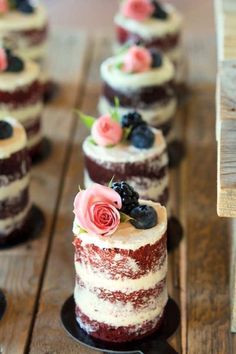 there are many small cakes that have flowers on top of them, and one has blueberries in the middle