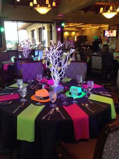 a dining room with tables covered in black table cloths and neon colored napkins