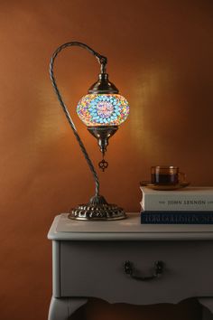 a table with a lamp on top of it next to some books and a candle