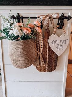 two baskets with flowers hanging on the wall next to a sign that says home sweet home