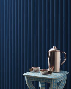 a table with two bowls and a pitcher on it next to a blue striped wall