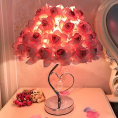 a heart shaped lamp sitting on top of a table next to a vase filled with flowers