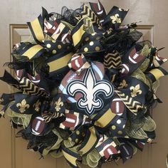 a new orleans saints deco mesh wreath on the front door with footballs and fleurons