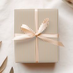 a gift box with a ribbon on top of it next to silverware and flowers