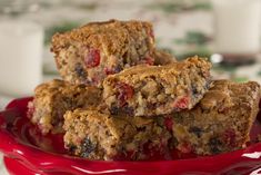 three pieces of fruit and oatmeal breakfast bars on a red plate with a glass of milk in the background