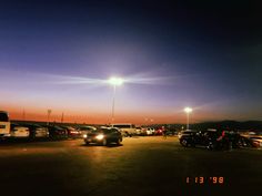 a parking lot filled with lots of parked cars under a street light at night time