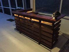 an outdoor bar made out of pallets and wooden crates is lit up at night