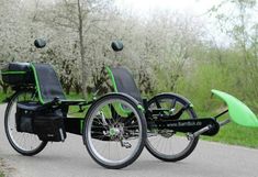 two bikes with green seats are parked on the side of the road in front of some trees