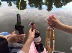 two women are holding wine bottles near the water