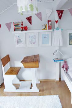 a bedroom with white walls and wooden floors, decorated with red and white pennants