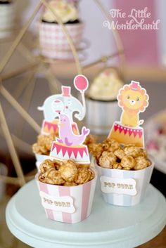 two cups filled with food sitting on top of a white cake stand next to a ferris wheel