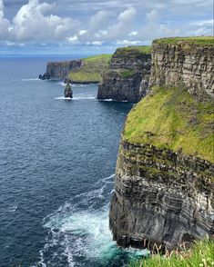 cliffs on the edge of an ocean with green grass and blue water in the foreground