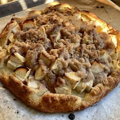 an apple pie sitting on top of a pan covered in crumbled toppings