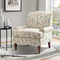 a white chair sitting on top of a rug in a living room next to a window