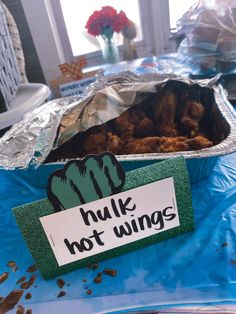 a tin foil container filled with food on top of a blue tablecloth covered table