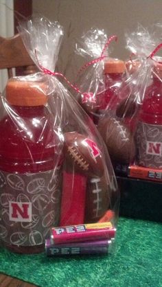 two plastic bottles with footballs and pencils wrapped in cellophane, sitting on a table