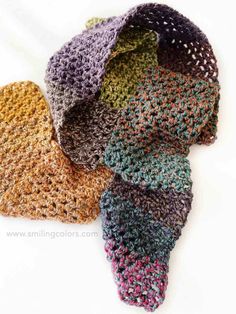 four crocheted hats sitting on top of each other in different colors and sizes