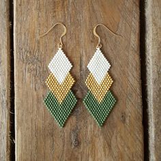 a pair of earrings made out of seed beads on a wooden table with a piece of wood in the background