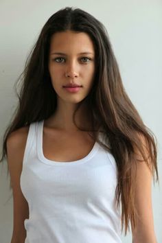 a woman with long brown hair wearing a white tank top