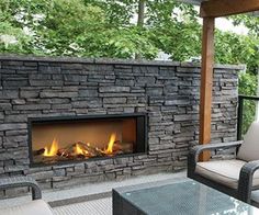 an outdoor fireplace is shown in the middle of a patio with two chairs and a table