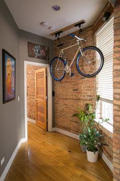 there is a bike hanging from the ceiling in this room with wood flooring and brick walls