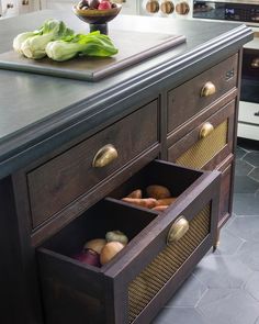 an open drawer in the middle of a kitchen counter with some vegetables on top of it