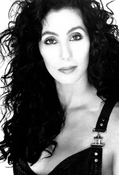 a black and white photo of a woman with long curly hair wearing a bra top