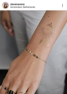 a woman's arm with a sun tattoo on the left side of her wrist