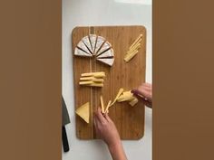 someone is cutting up some food on a wooden board with scissors and cheese wedges