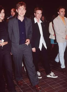 a group of young men standing next to each other on a tile floor in front of people