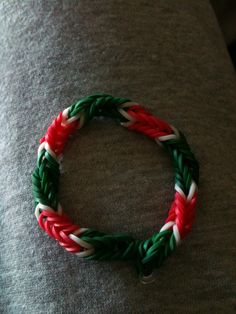 a red, white and green bracelet sitting on top of a person's arm